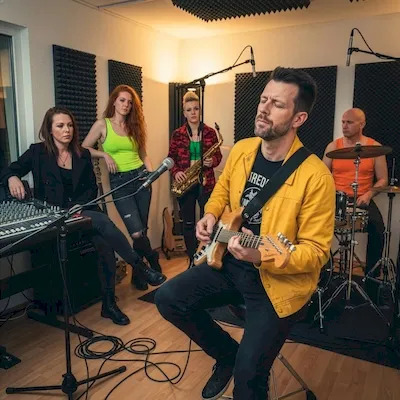 Art Vinger in gelber Jacke mit akustischer Gitarre im Studio