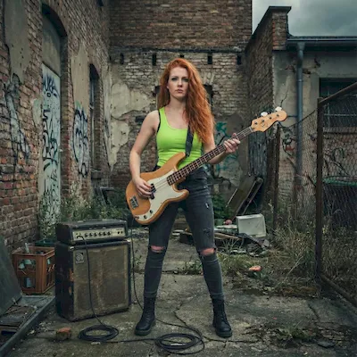 Lowla Beit mit leuchtend roten Haaren und neongrünem Top, Bass in der Hand